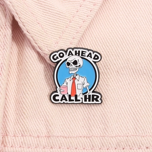 Detail of funny skeleton enamel pin on pink denim with GO AHEAD CALL HR slogan text