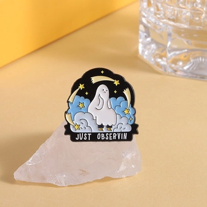 Macro detail of Just Observing cartoon ghost enamel pin on a pink decorative crystal