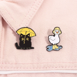Détail de broches en émail avec un chat noir et un canard portant des bottes de pluie