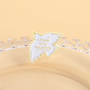 Detail of white dove enamel pin with yellow outlines and I Stand With Palestine text