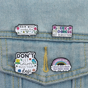 Lot de quatre pin's en émail motivants avec motifs arc-en-ciel et fleurs sur denim