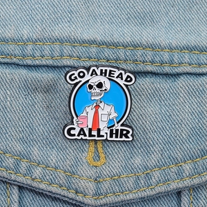 Skeleton enamel pin with GO AHEAD CALL HR text on blue denim background for work outfit