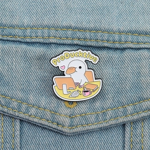 Cute enamel duck brooch pinned on denim jacket with ProDucktive pun and office desk design