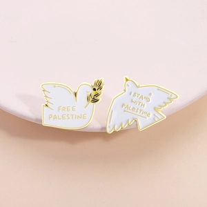 White dove enamel pins with olive branch and Free Palestine slogans in gold finish