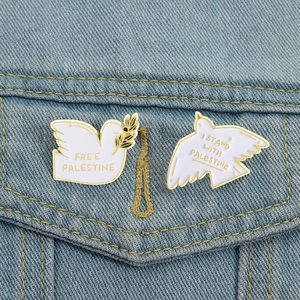 White enamel peace dove brooch pins with gold trim on denim fabric, set of two pins