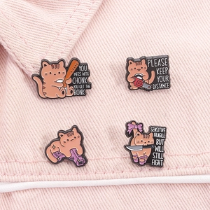 Détail de quatre épingles en émail de chat orange avec des motifs d'outils rigolos