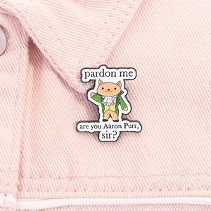 Gros plan d'un pin's chat en costume vert sur un fond de tissu denim rose vif