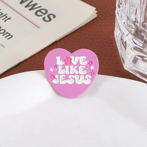 Broche cœur rose avec texte LOVE LIKE JESUS et motifs floraux sur une assiette blanche