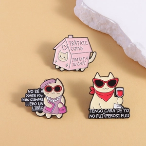 Three-piece enamel cat pins set with Spanish text on a beige minimalist background