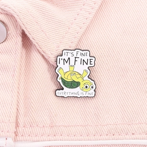 Detail of funny turtle enamel pin with humorous slogans on pink denim fabric background