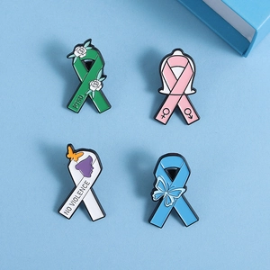 Lot de quatre pin's émaillés aux rubans vert, rose, blanc et bleu sur un fond bleu clair
