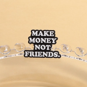 Détail macro de la broche émaillée avec lettrage Make Money Not Friends et bordure