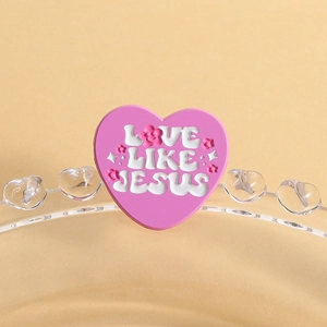 Détail macro du charm cœur rose avec texte LOVE LIKE JESUS en relief et fleurs