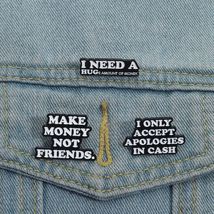 Trois pin's en émail minimalistes avec slogans humoristiques sur une veste en jean bleue