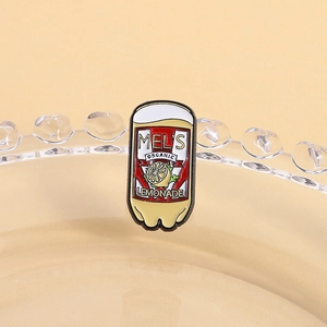 Macro shot of Mel's Organic Lemonade enamel pin on a glass dish, vintage style