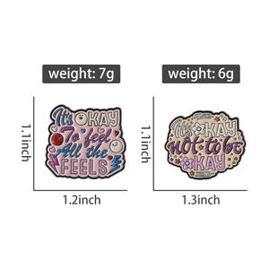 Detailed view of two motivational enamel pins with heart and floral designs