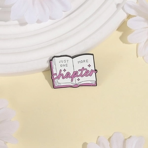 Cartoon book enamel pin with Just One More Chapter text on a daisy decor background