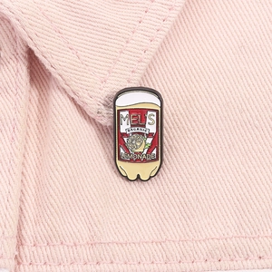 Detail of Mel's Organic Lemonade enamel pin with lemon design on pink denim fabric