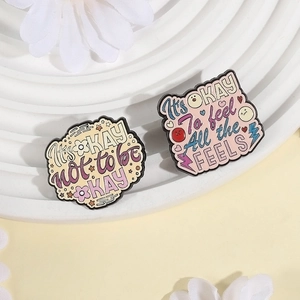 Enamel pins with motivational quotes It's OKAY not to be OKAY on white floral background
