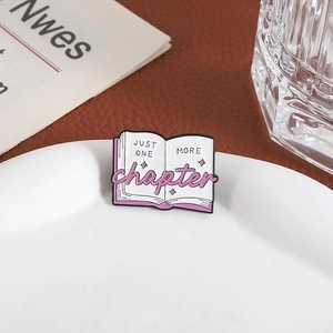 Pink enamel book brooch featuring 'JUST ONE MORE chapter' text and star decorations