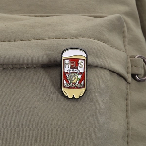 Detailed close-up of a vintage enamel lemon soda pin on a green canvas backpack