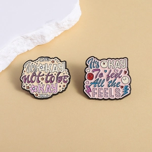 Detail of metal enamel badges with motivational quotes on a beige textured surface