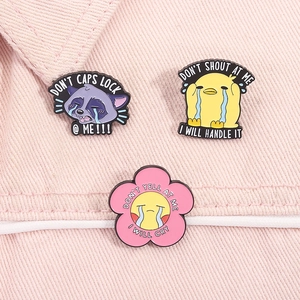 Three funny enamel animal pins pinned on pink denim with cute raccoon and duck motifs