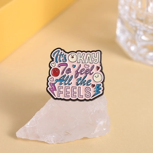 Enamel pin featuring It's OKAY To feel All the FEELS quote on crystal base