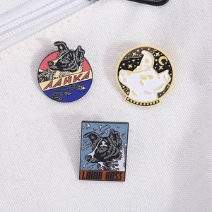 Detail of three Laika Space Dog enamel pins with gold trim on white canvas texture