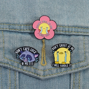 Three creative enamel pins featuring sad cartoon chick, raccoon, and flower on denim