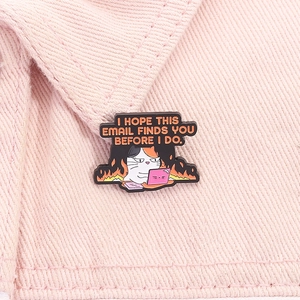 Detail of an angry office cat enamel pin with funny quote on pink denim background