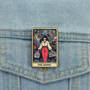 Creative enamel book brooch with ADHD tarot card design pinned on a denim jacket pocket