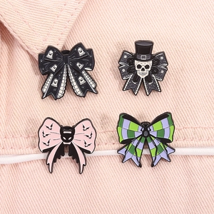 Macro detail of four Halloween enamel bow pins featuring ghosts, bats and skull motifs