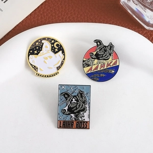 Three Soviet space dog Laika enamel pins set displayed on a white ceramic plate