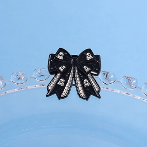 Close-up of gothic black bow enamel pin with white ghost patterns for Halloween