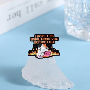 Detail of angry office cat enamel pin with flames and humorous office culture text