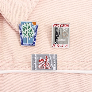 Close-up of three Russian folk enamel pins featuring birch trees and characters on fabric
