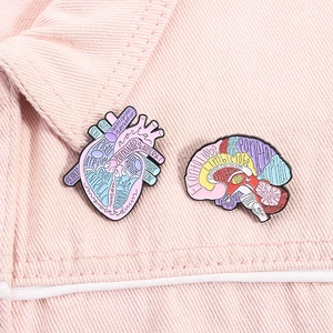 Detail showing anatomical heart and brain enamel pins on a pink denim collar