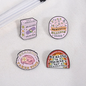 Detailed view of four mental health enamel pins on white canvas fabric background