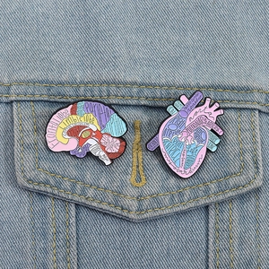 Detailed brain and heart anatomy enamel pins on a denim jacket for medical students