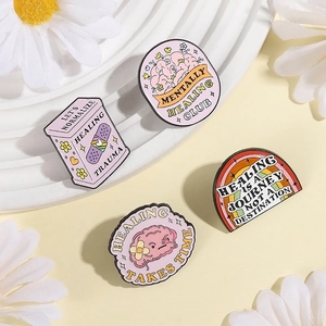 Pink mental health enamel pins set with brain and healing box designs on white board