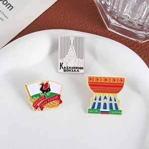 Lot de trois badges émaillés Kazan Russie posés sur une assiette en céramique blanche