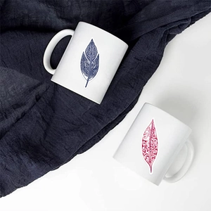 Détail de deux mugs en céramique blanche avec motifs de plumes style mandala colorés