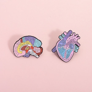 Creative colorful enamel pins featuring anatomical brain and heart shapes on pink background