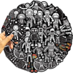 Close-up of a hand holding a black and white astronaut sticker with matte finish detail
