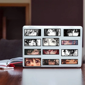 Close-up of anime eye graffiti stickers applied on a white laptop lid with a wood background