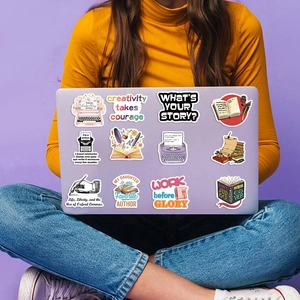 Close-up of writer-themed stickers featuring vintage typewriters and books on a purple laptop