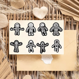 Close-up of 8 black and white astronaut stickers on kraft paper with rustic decor
