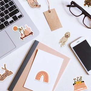 Flat lay of artistic BOHO stickers with leopard and rainbow patterns on a laptop and notebook