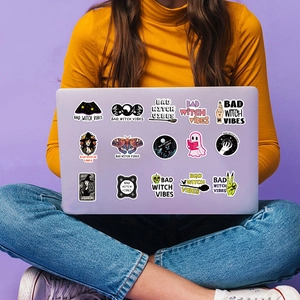 Detail of waterproof Bad Witch Vibes stickers on a purple laptop with gothic designs